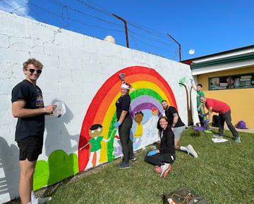 Volunteers painting the wall at the Christmas Holiday Experience project in San Jose, Costa Rica with IVHQ