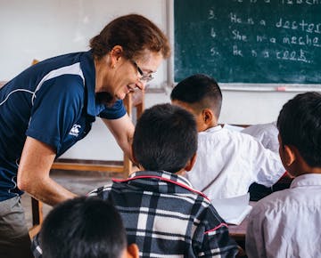 Senior volunteer teaching children in Laos with IVHQ